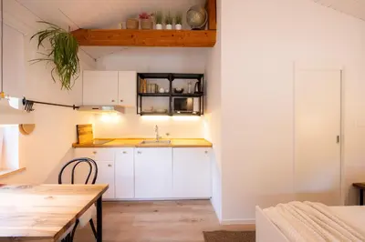 a kitchen with white cabinets and a wooden table at Studio Apartment Jož' in Spodnja Lipnica