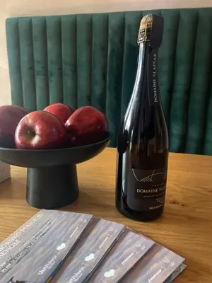 a bottle of wine and a bowl of apples on a table at Apartment on the ski slope Pohorje 11 in Pohorje