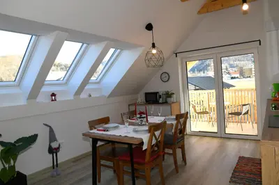 a dining room with a table and chairs and windows at Apartments Ajda in Bohinj