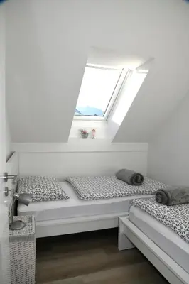 two beds in a white room with a window at Apartments Ajda in Bohinj