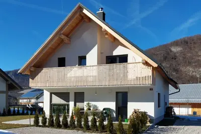 a white house with a wooden roof at Apartments Ajda in Bohinj