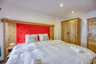 a bedroom with a large white bed with a red headboard at Apartments Viktor in Rateče
