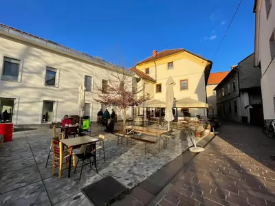 a group of people sitting at tables in front of a building at Super Small Micro-Treehouse in the centre in Ljubljana