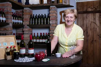 a woman standing at a table with a wine glass at Gostišče - Guest house STARI HRAST in Ljutomer