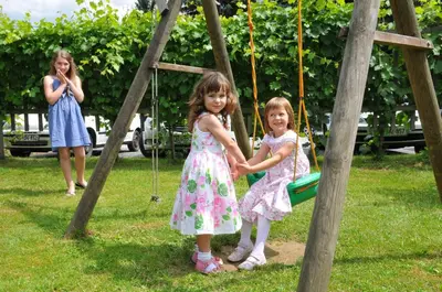 two little girls in dresses playing on a swing at Gostišče - Guest house STARI HRAST in Ljutomer