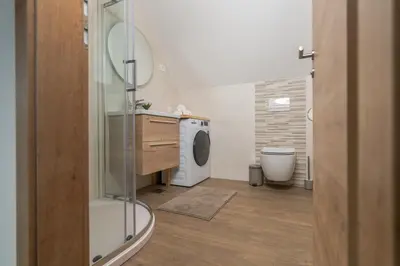 a bathroom with a shower and a washing machine at Apartment Orehar in Bohinj