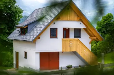 a house with a gambrel roof and red doors at Apartment Orehar in Bohinj