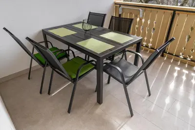 a dining room table with four chairs and a glass at Apartment Orehar in Bohinj