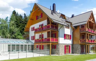 a building with red and white balconies next to a house at Stunning Apartment In Pohorje With Wifi in Pohorje
