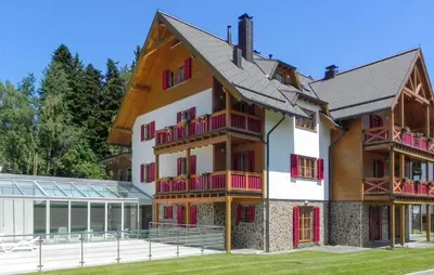 a building with red and white balconies next to a house at 1 Bedroom Gorgeous Apartment In Pohorje in Pohorje