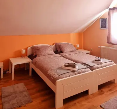 a large bed in a room with orange walls at Apartmaji Medved, brezplačno parkiranje in Tacen