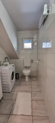 a bathroom with a toilet and a washing machine at Apartmaji Medved, brezplačno parkiranje in Tacen