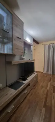 a living room with a large tv and a wooden floor at Apartmaji Medved, brezplačno parkiranje in Tacen