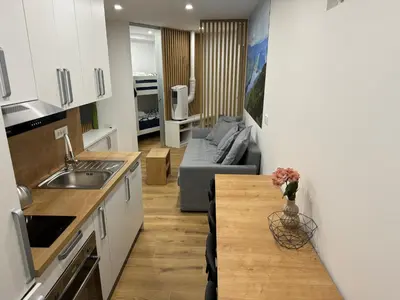 a kitchen and living room with a couch and a table at Apartma Tisa Bohinj-no outside windows in Bohinj