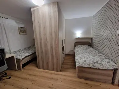 a small bedroom with two beds and a wooden closet at Vila Lastovka in Ljubljana