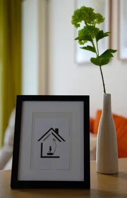 a picture of a house on a table next to a vase at Apartma Pikabooth in Topolšica