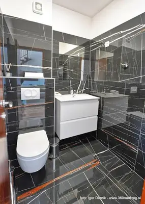 a black tiled bathroom with a toilet and a sink at Terme Olimia - Apartment 407 in Podčetrtek