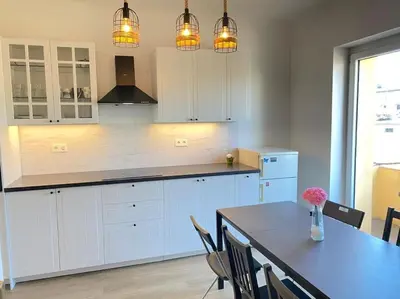 a kitchen with white cabinets and a table with chairs at Apartment Herberstainova in Ljubljana