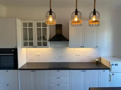a kitchen with white cabinets and three lights at Apartment Herberstainova in Ljubljana