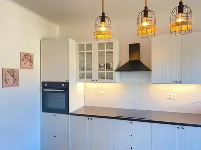a kitchen with white cabinets and black appliances with lights at Apartment Herberstainova in Ljubljana