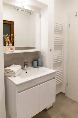 a white bathroom with a sink and a mirror at Oliver street apartment Vipava - 50m from city center in Vipava