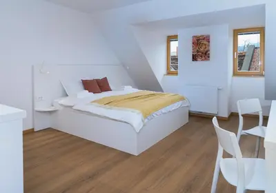 a white bedroom with a bed and a table and chairs at Primus apartments in Ljubljana