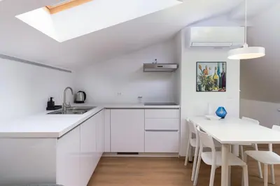 a kitchen with white cabinets and a white table at Primus apartments in Ljubljana