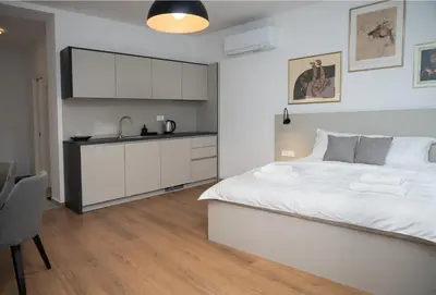 a bedroom with a large white bed and a kitchen at Primus apartments in Ljubljana