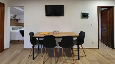 a dining room table with four chairs and a tv on a wall at HIŠKA TIBAUT 122 vključene kopalne karte in Veržej