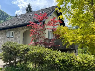 a house with red flowers on the side of it at Creek House Bohinj in Bohinj