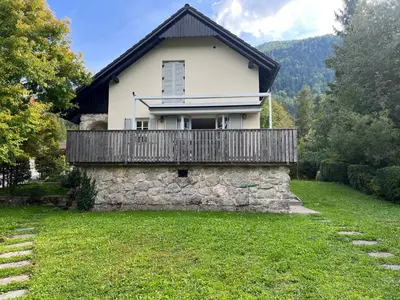 a house with a balcony on top of a stone wall at Creek House Bohinj in Bohinj