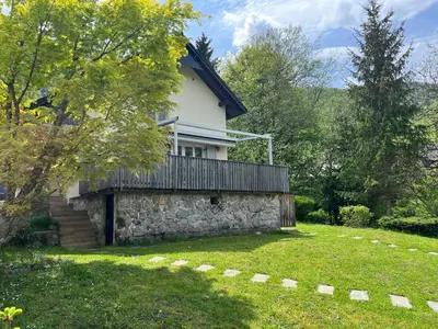 a house with a stone wall in a yard at Creek House Bohinj in Bohinj