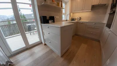 a kitchen with white cabinets and a large window at Creek House Bohinj in Bohinj