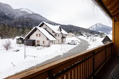 a view from the balcony of a house with snow at Waterfall Apartment - Cozy Mountain Retreat in Kranjska Gora