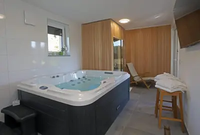 a large bath tub in a bathroom with a stool at Hiša Štolc in Gornja Radgona