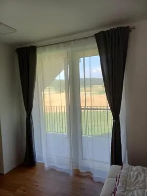 a bedroom with a large window with curtains at Hiša Štolc in Gornja Radgona