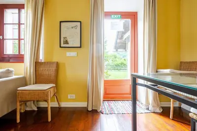 a yellow room with a table and a window at Bela Luna - Charming Garden Cottage near Lake Bled in Bohinjska Bela