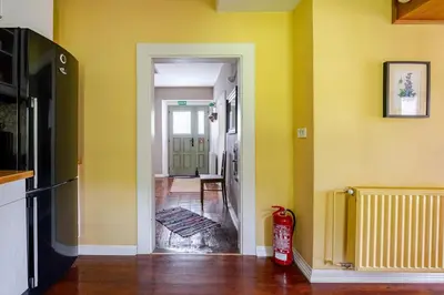 a kitchen with yellow walls and a hallway at Bela Luna - Charming Garden Cottage near Lake Bled in Bohinjska Bela