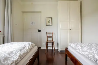 a bedroom with a bed and a chair next to a door at Bela Luna - Charming Garden Cottage near Lake Bled in Bohinjska Bela