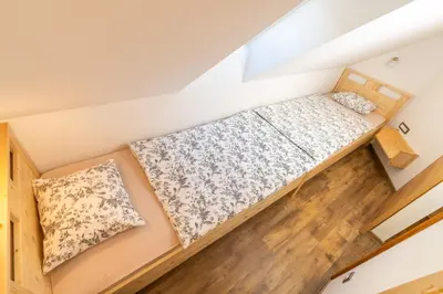 an attic bedroom with a bed and pillows at Apartments and Rooms Hodnik Slavko in Bohinj