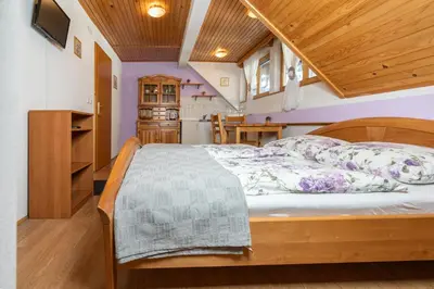 a bedroom with a bed with a wooden frame at Apartments and Rooms Hodnik Slavko in Bohinj