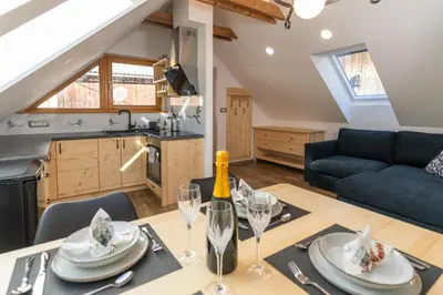a kitchen and living room with a dining table and a blue couch at Apartments and Rooms Hodnik Slavko in Bohinj