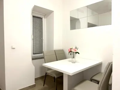a white dining room with a white table and chairs at Grajski kamen apartment in Maribor