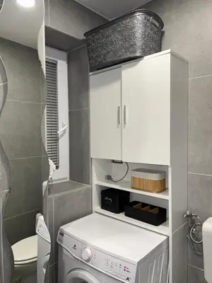 a laundry room with a washer and a white cabinet at Grajski kamen apartment in Maribor