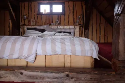 a bed in a wooden cabin with a window at Wooden love nest in Vransko