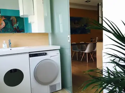 a washing machine in a kitchen next to a dining room at Ljubljana City Apartment Metelkova in Ljubljana