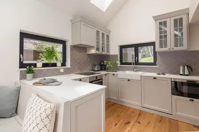 a white kitchen with white cabinets and windows at Villa Polje in Bohinj