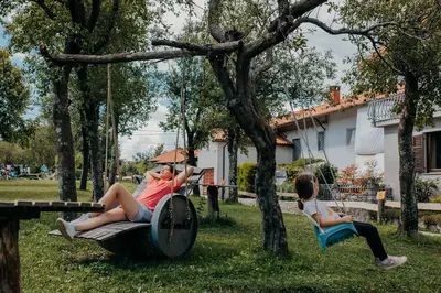 two people sitting on a swing with an umbrella at DS Camping in Grgar