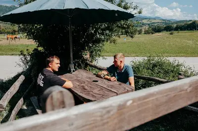 two men sitting at a table under an umbrella at DS Camping in Grgar