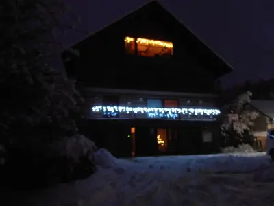 a house with christmas lights in the window at night at Bed & Breakfast Base Camp in Križe